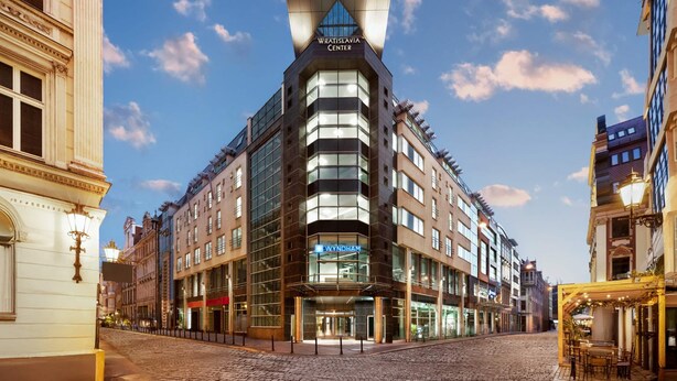 A modern hotel with a distinctive triangular roof, a 'Wynham' sign, and a cobblestone street in the foreground. - Wyndham Wroclaw Old Town (Wroclaw)