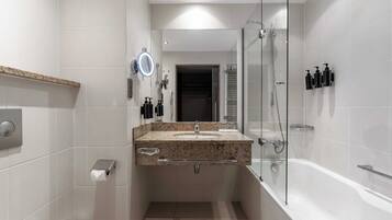 A modern bathroom with a glass-enclosed shower, a vanity with a granite countertop, and a toilet.