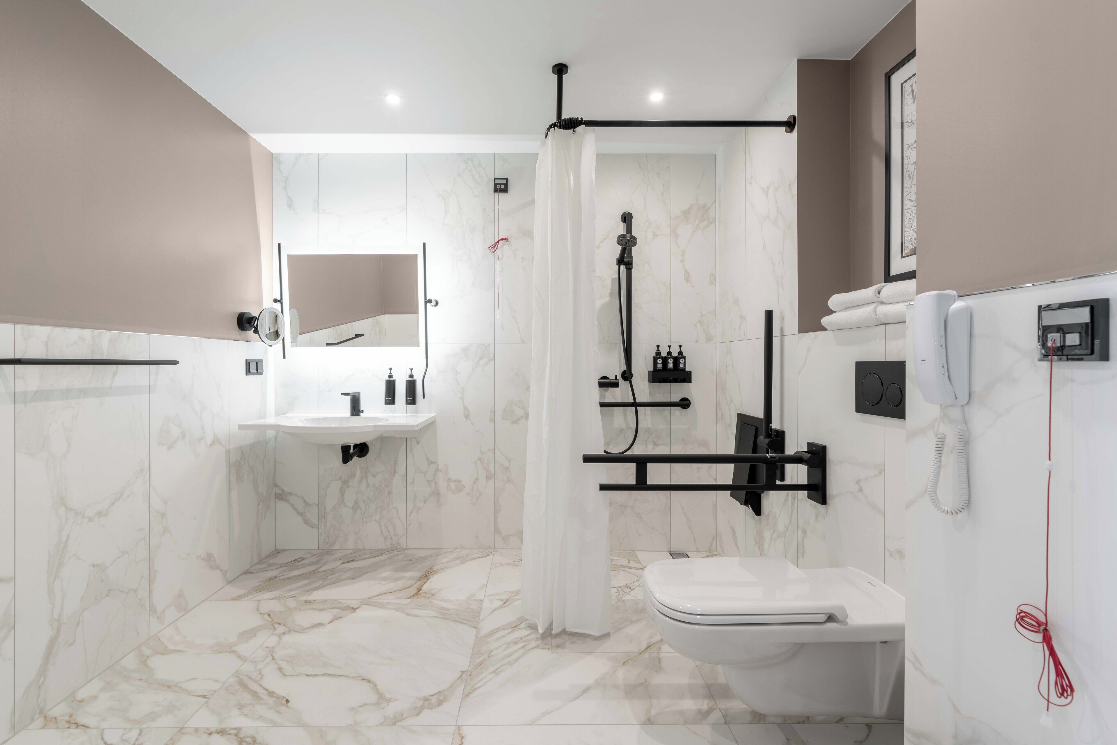 A modern bathroom with a marble floor, a white sink, a toilet, and a shower area.