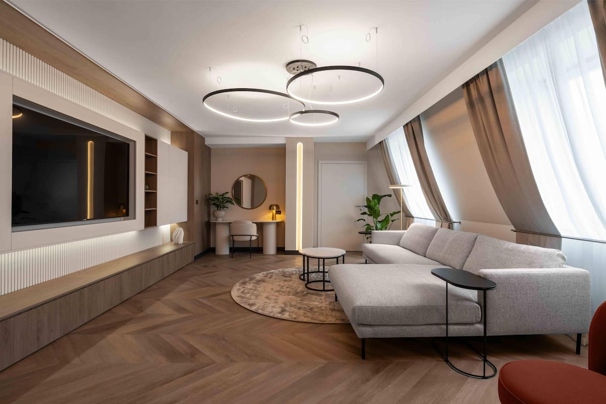 A modern living room with a large flat-screen TV, a sofa, a coffee table, and a round rug.