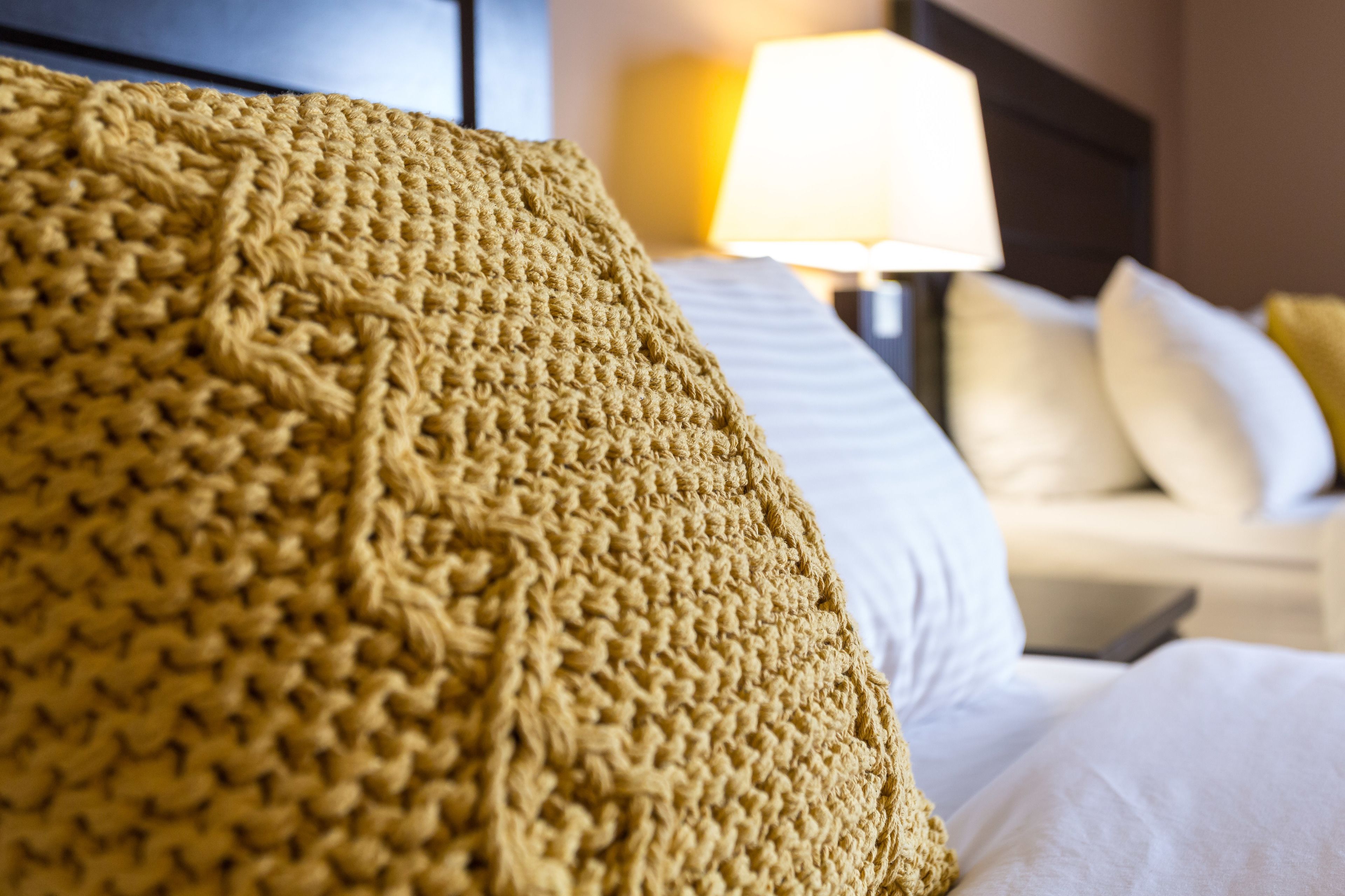A close-up of a textured, knitted throw blanket on a bed.