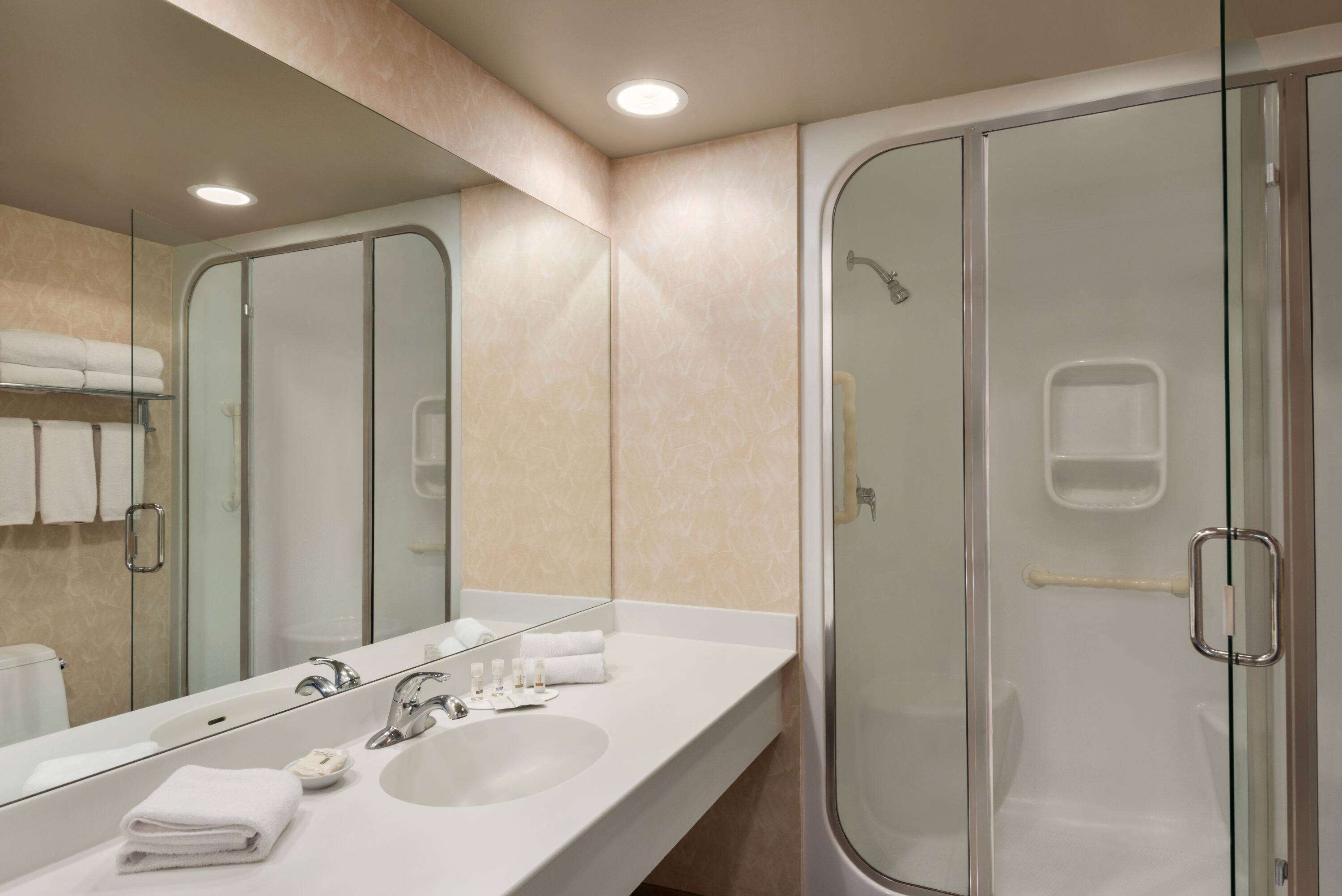 Un baño moderno con un espejo grande, lavabos dobles y ducha con cerramiento de vidrio.