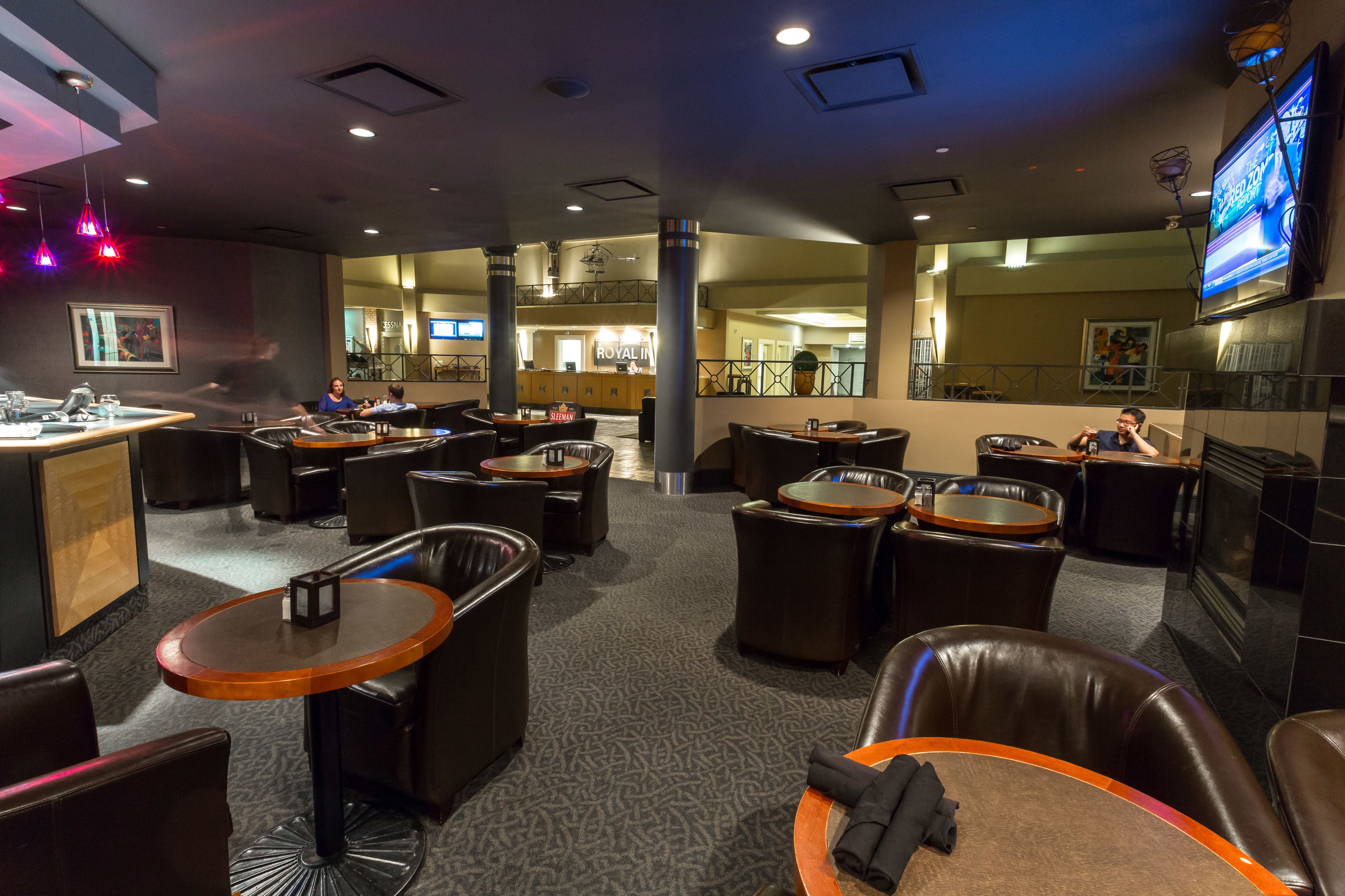 A hotel lobby with multiple seating areas, a reception desk, and a TV screen.