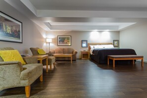 Relax in a stylishly appointed room with a sofa, armchairs, and a neatly made bed.