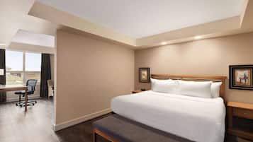Una habitación de hotel con una cama grande, un banco, un escritorio y una silla.