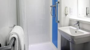 Ein modernes Badezimmer mit einer gläsernen Dusche, einem weißen Waschbecken und einem Handtuchhalter.