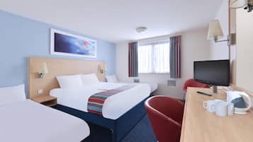 A hotel room with a bed, two bedside tables, a desk with a chair, a television, and a window with curtains.
