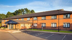 Ein Travelodge Hotel mit Backsteinfassade, überdachter Eingang und Parkplatz.