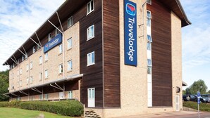 A Travelodge hotel with a brick facade, multiple windows, and a sign indicating its name. - Travelodge Ashford (Ashford)