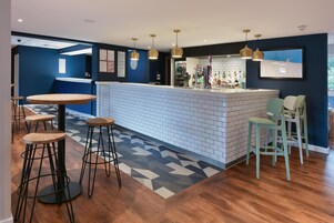 Una zona de bar moderna con mostrador de ladrillo blanco, taburetes de madera e iluminación colgante.