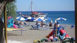 Une plage avec des chaises longues, des parasols et un espace de jeux.