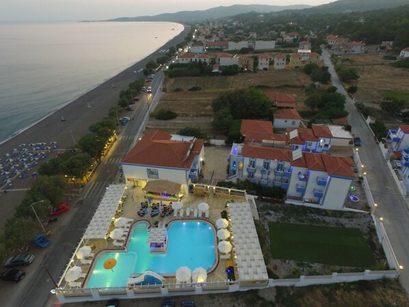 Vista aérea de una zona costera con un complejo de piscinas, edificios residenciales cercanos y una playa.
