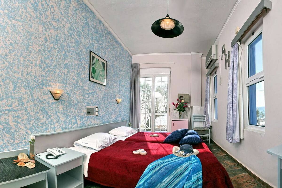 A hotel room with two beds, a desk with a telephone, a chair, and a window with curtains.