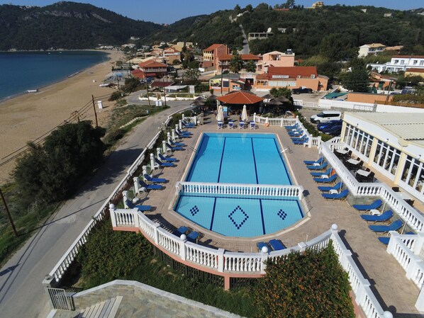 A resort with a large swimming pool, lounge chairs, and a view of the beach. - Belle Helene Hotel (Corfu)