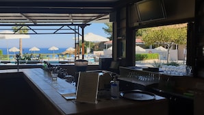 Zona de bar con vistas a una piscina y sombrillas, un expositor de menú y una botella de desinfectante de manos.