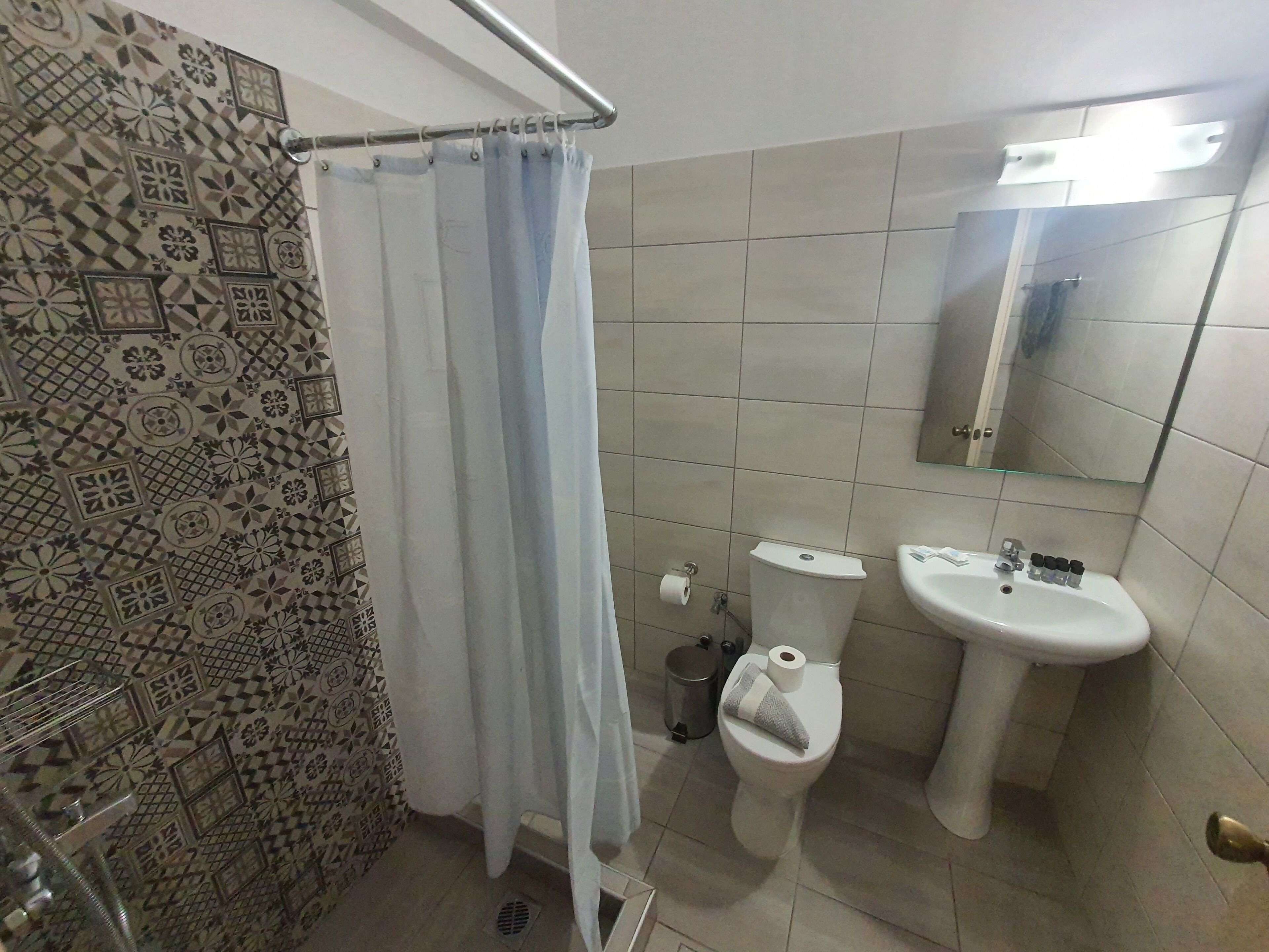 Un baño con cortina de ducha estampada, inodoro, lavabo y espejo.
