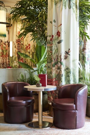 A room with two leather chairs, a small round table, and a potted plant. - The Trafalgar St. James London, Curio Collection by Hilton (London)