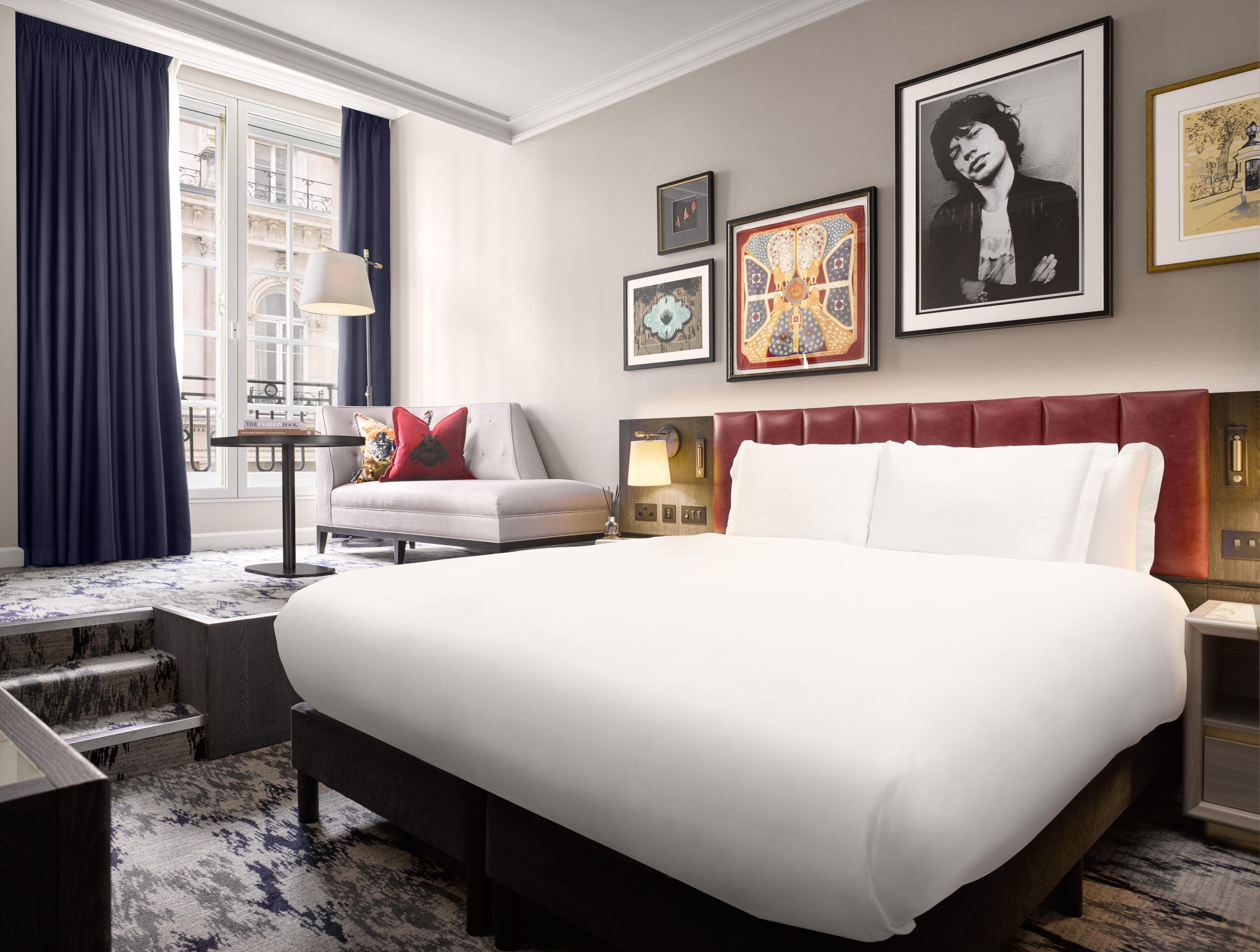 Una habitación de hotel con una cama grande, un sofá, un escritorio y una ventana con cortinas.