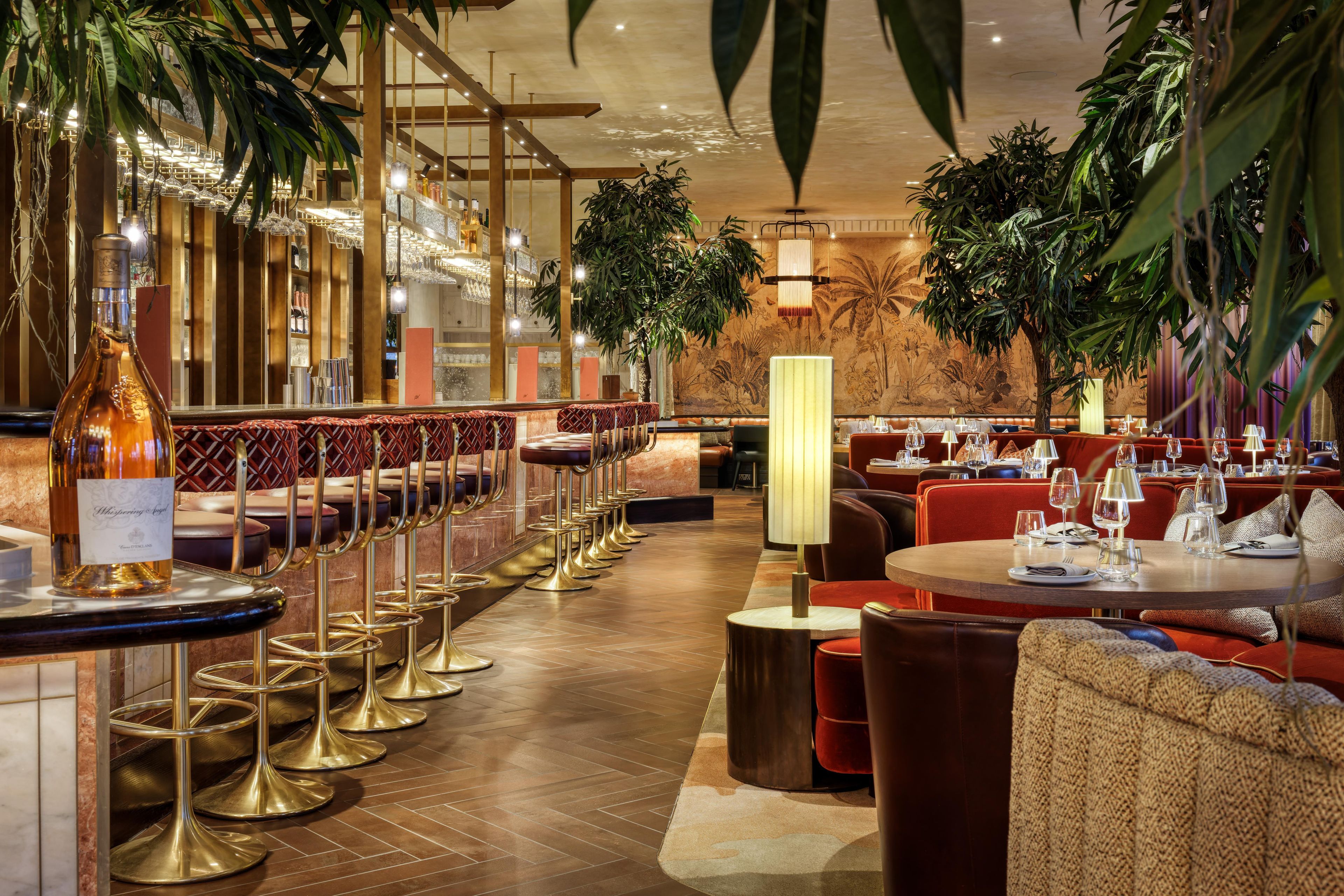 A restaurant interior with bar seating, round tables, and a warm ambiance.