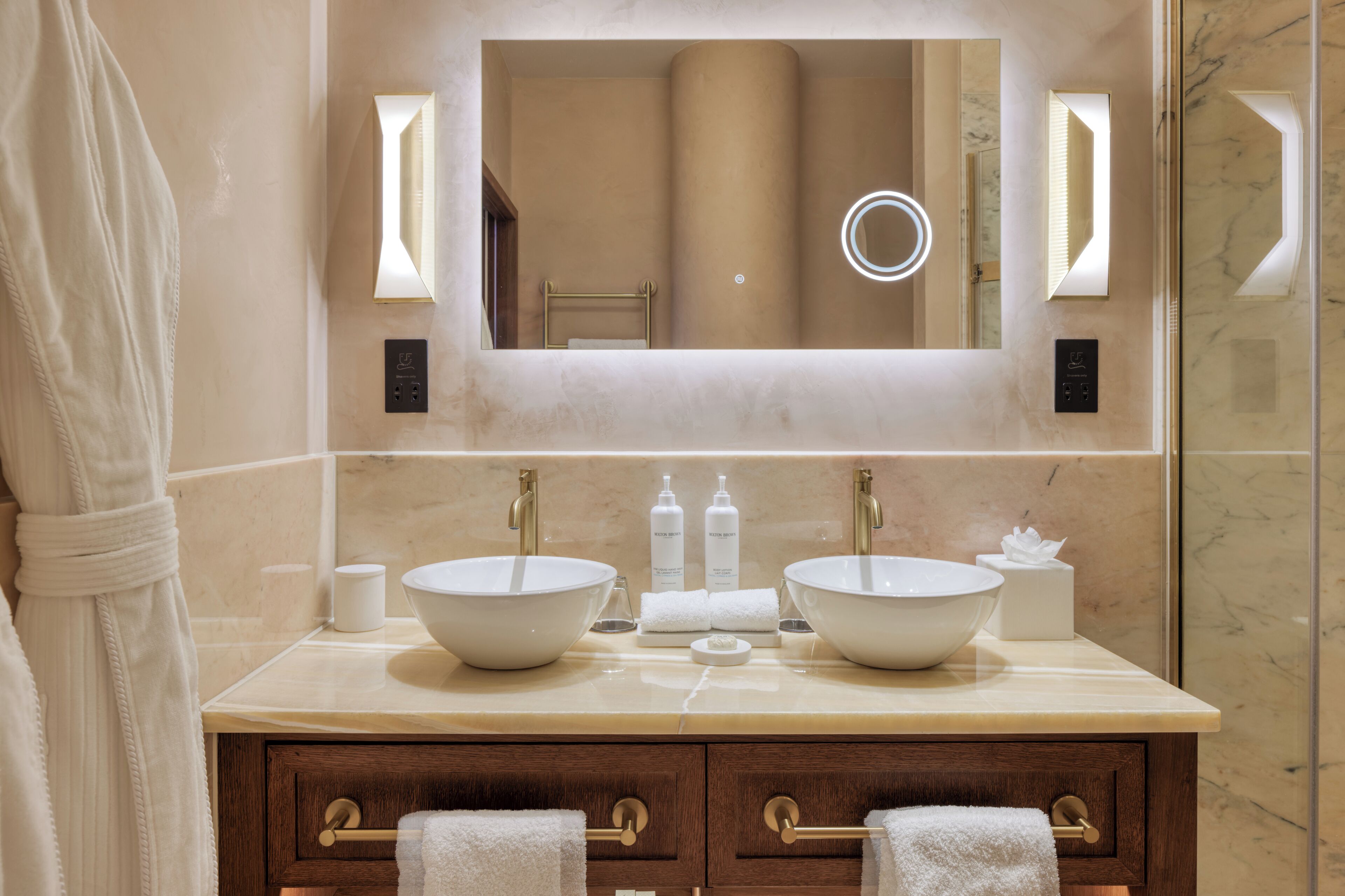 A bathroom with two sinks, a mirror, and a robe.