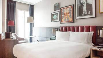 Habitación de hotel con una cama grande, un escritorio, una silla y obras de arte en las paredes.