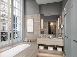 Ein modernes Badezimmer mit einer großen Badewanne, zwei Waschbecken, einem Spiegel und einem Handtuchhalter.