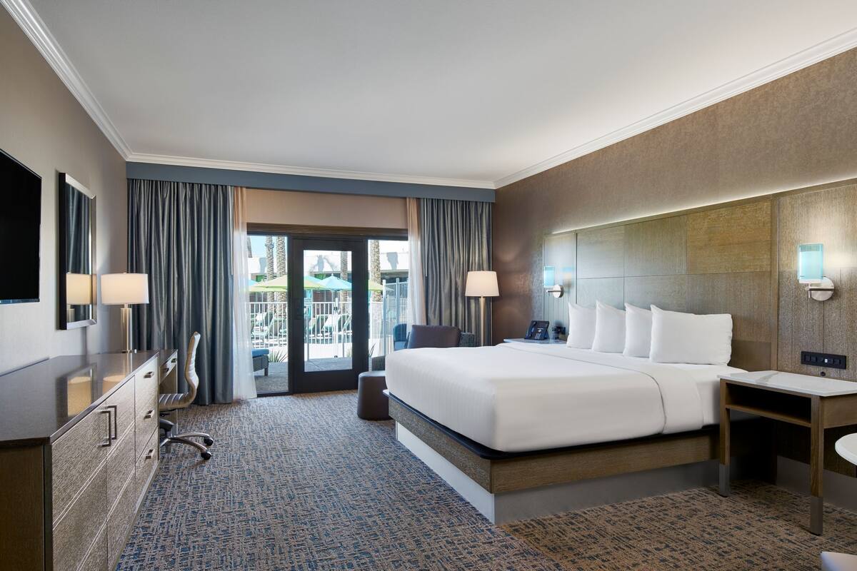 Une chambre d’hôtel équipée d’un lit, d’un bureau, d’une chaise et offrant une vue sur l’espace extérieur.