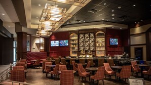 Ein Restaurant mit Barbereich, mehreren Fernsehern und verschiedenen Sitzgelegenheiten, darunter gemütliche Sitzecken und Tische.