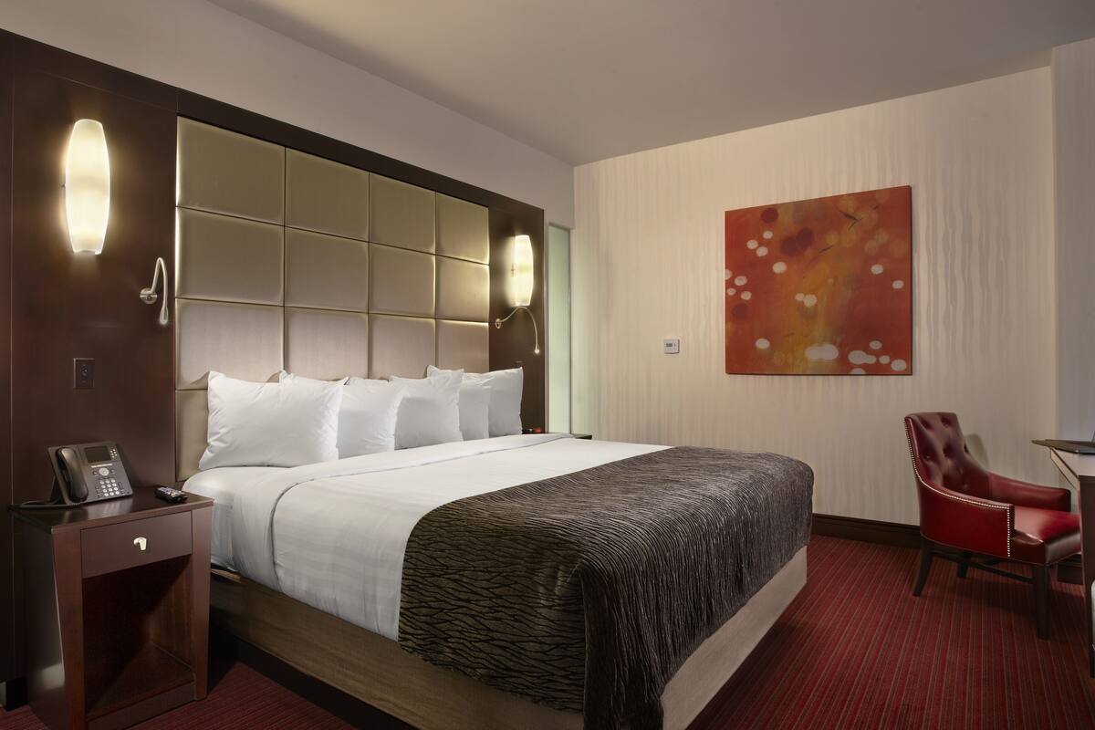 Une chambre d’hôtel avec un grand lit, un bureau avec un ordinateur portable, un téléphone et une chaise.