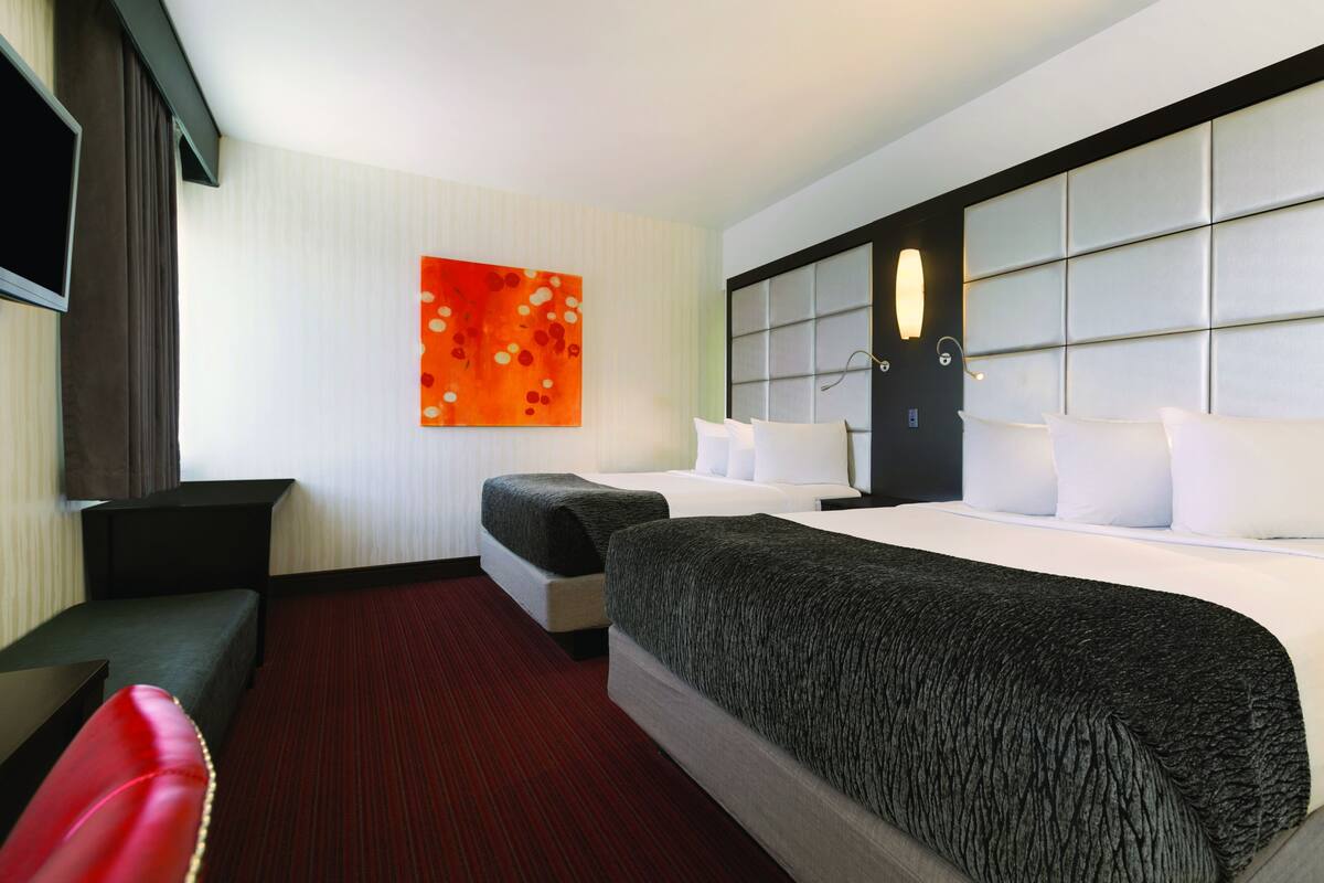 Une chambre d’hôtel avec un grand lit, un bureau, une chaise et un téléviseur.