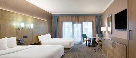 A hotel room with two beds, a desk, a chair, a TV, and a window with curtains.