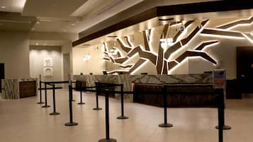 A reception area with a modern design, featuring a marble reception desk and a unique light pattern on the wall.