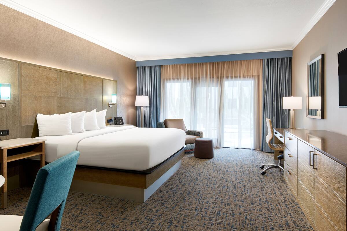 Une chambre d’hôtel avec un grand lit, un bureau, une chaise, une télévision et une salle de bain.