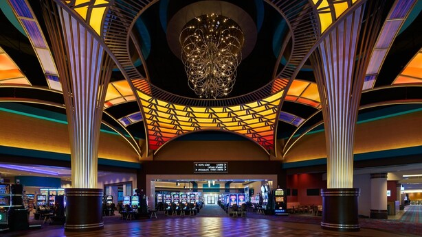 Eine großzügige Lobby mit hoher Decke, einem zentralen Kronleuchter und mehreren Spielautomaten.
