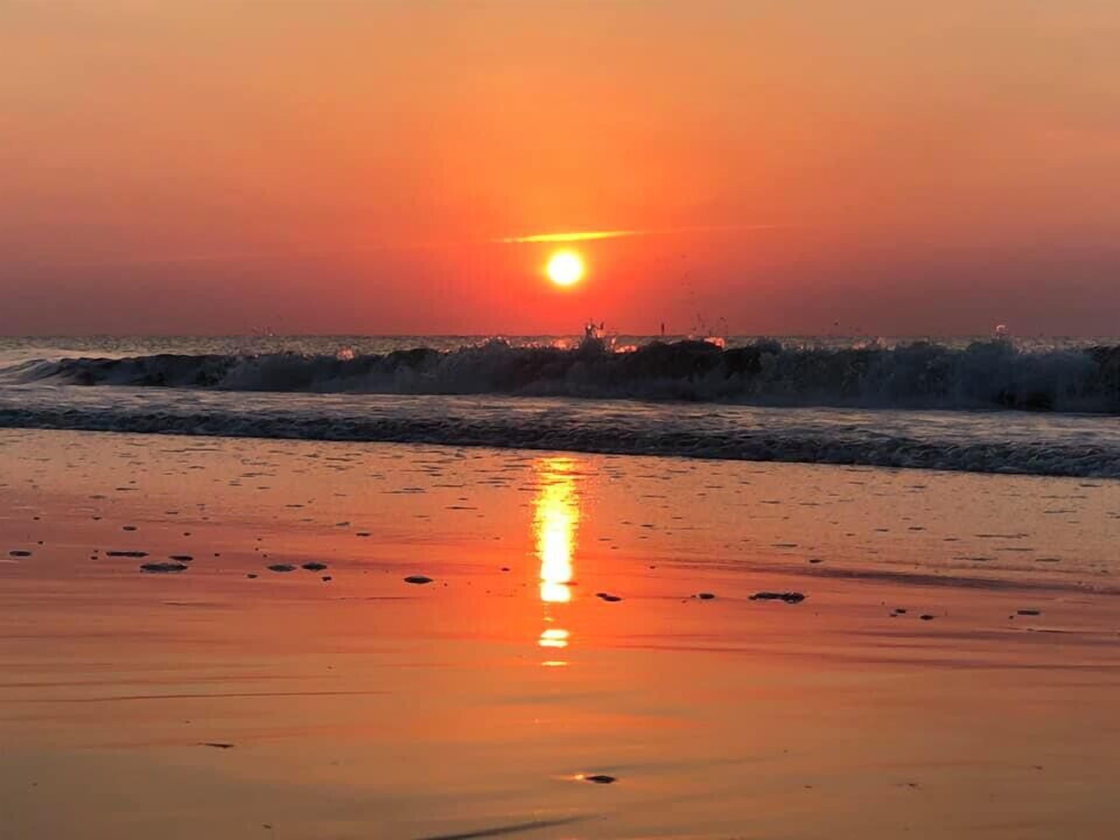 Un coucher de soleil sur une plage, avec des vagues.