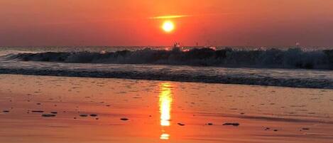 Un coucher de soleil sur une plage, avec des vagues.
