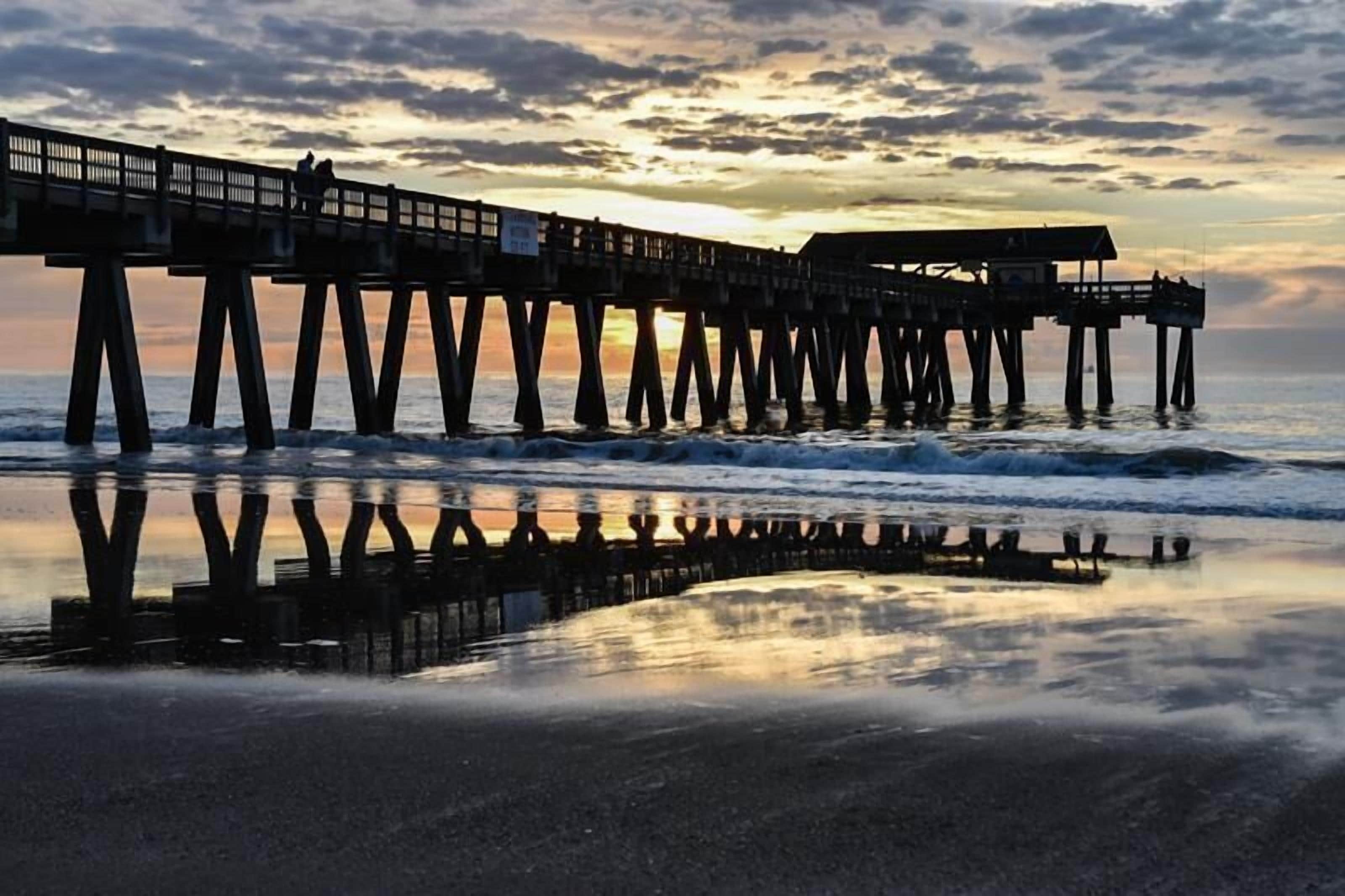 A pier extending into the water with a sunset in the background.