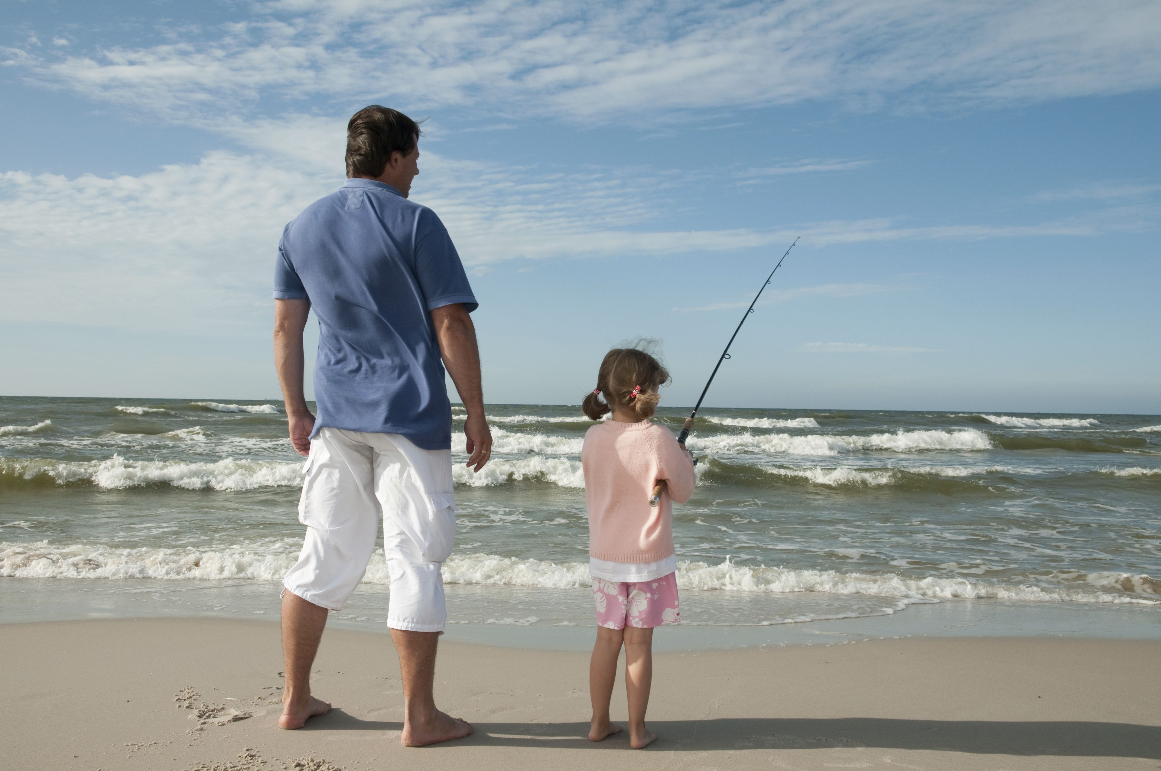A man and a child fishing on a beach.