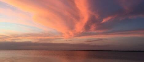 A calm body of water reflecting a sunset sky with clouds.
