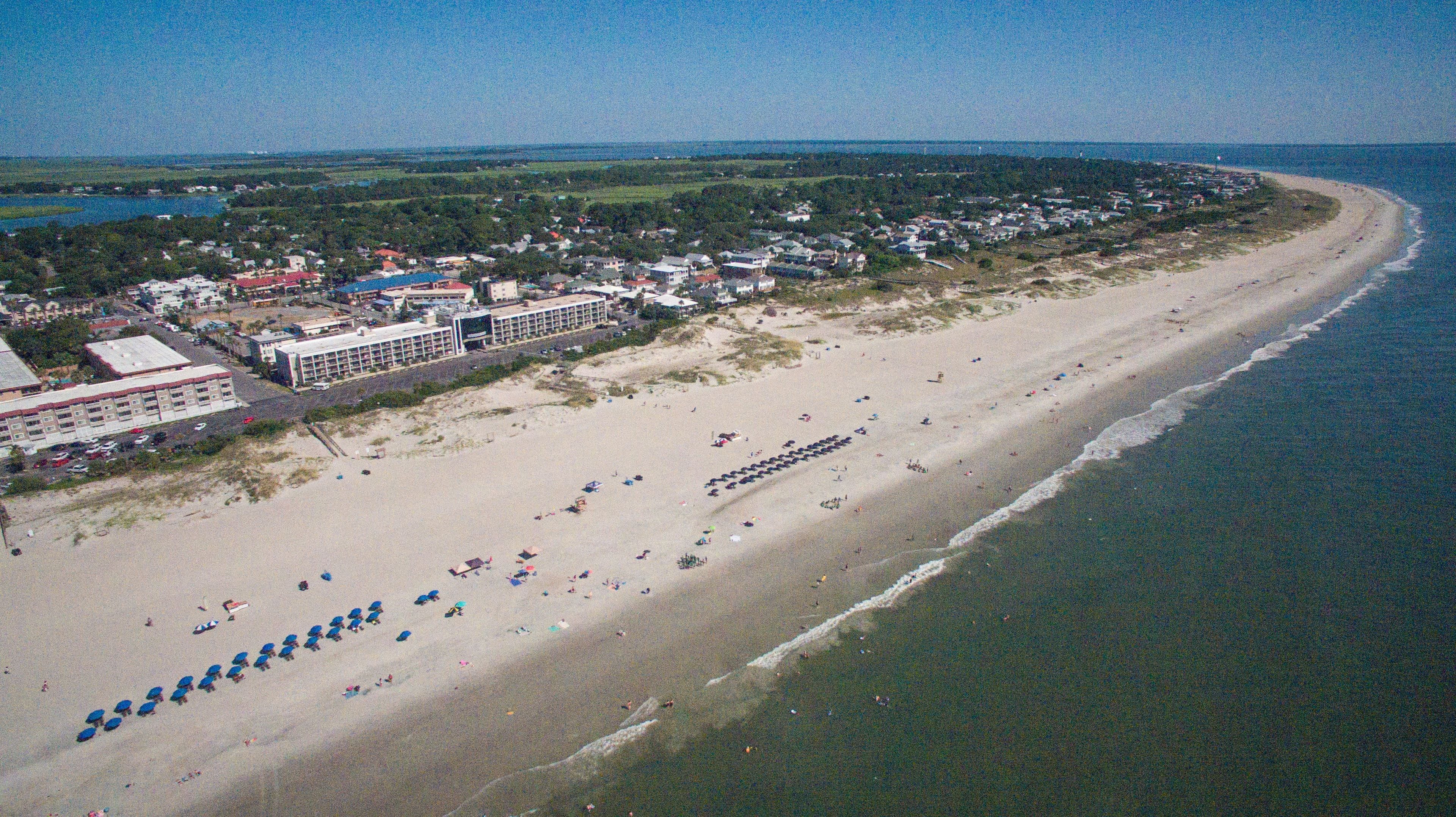 An aerial view of a beach with rows of umbrellas and beachgoers.