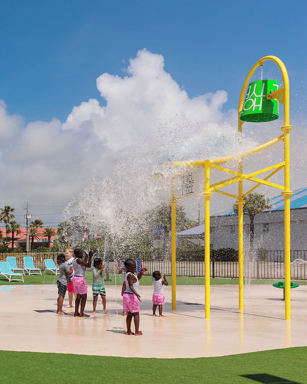 Un área de juegos con agua, una estructura amarilla y un cubo verde.