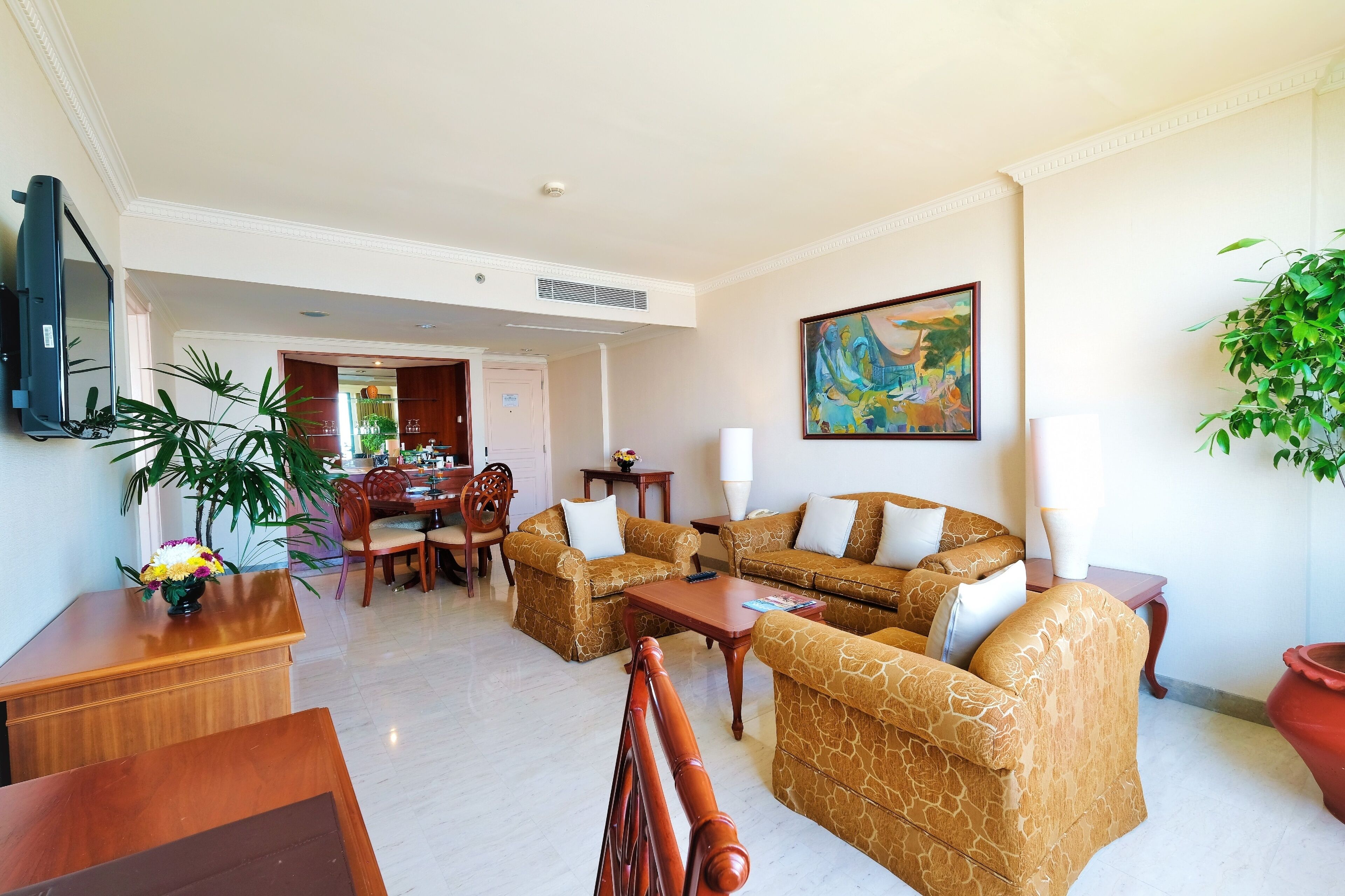 Ett hotellrum med en soffgrupp, en matplats, en TV och en tavla på väggen.