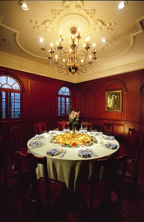 Un comedor formal con candelabro, mesa redonda y sillas tapizadas en rojo.
