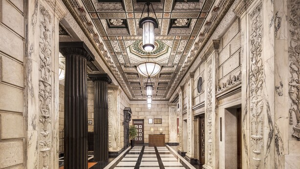 Un vaste hall d’entrée orné de colonnes de marbre, doté d’un sol à carreaux et de décorations élaborées au plafond.