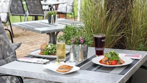An outdoor dining table with plates of food, drinks, and condiments. - Hotel ARTE Schwerin (Schwerin)