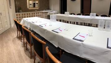 Un salón de conferencias con una larga mesa, sillas y una planta en maceta.