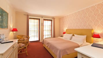 A hotel room with a bed, two bedside tables, a desk, a chair, and a window with blinds.