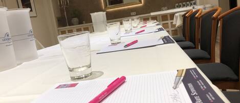 Un salón de conferencias con una larga mesa, vasos de agua, blocs de notas y bolígrafos.