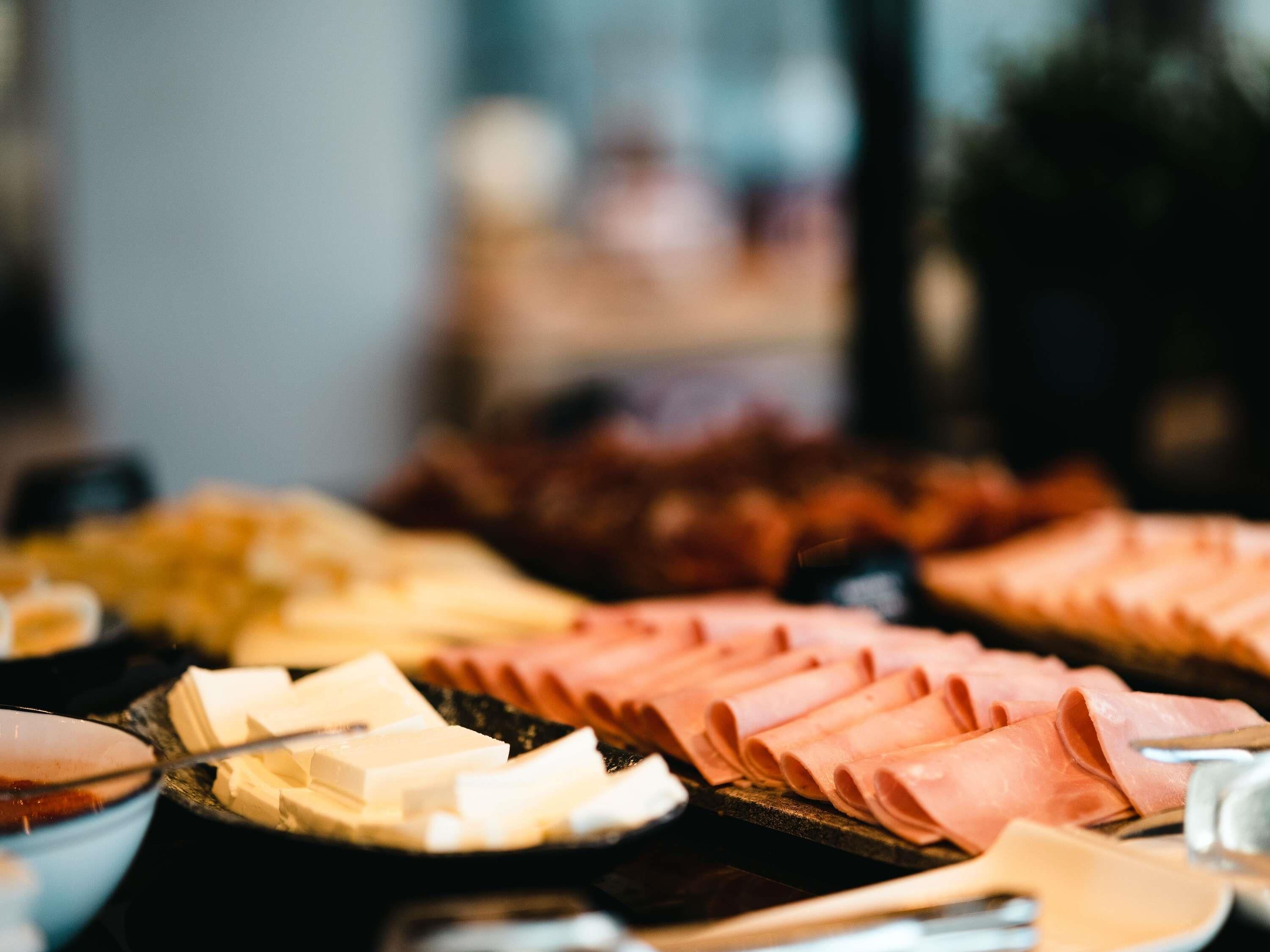 A buffet with various food items including sliced meats and cheeses.