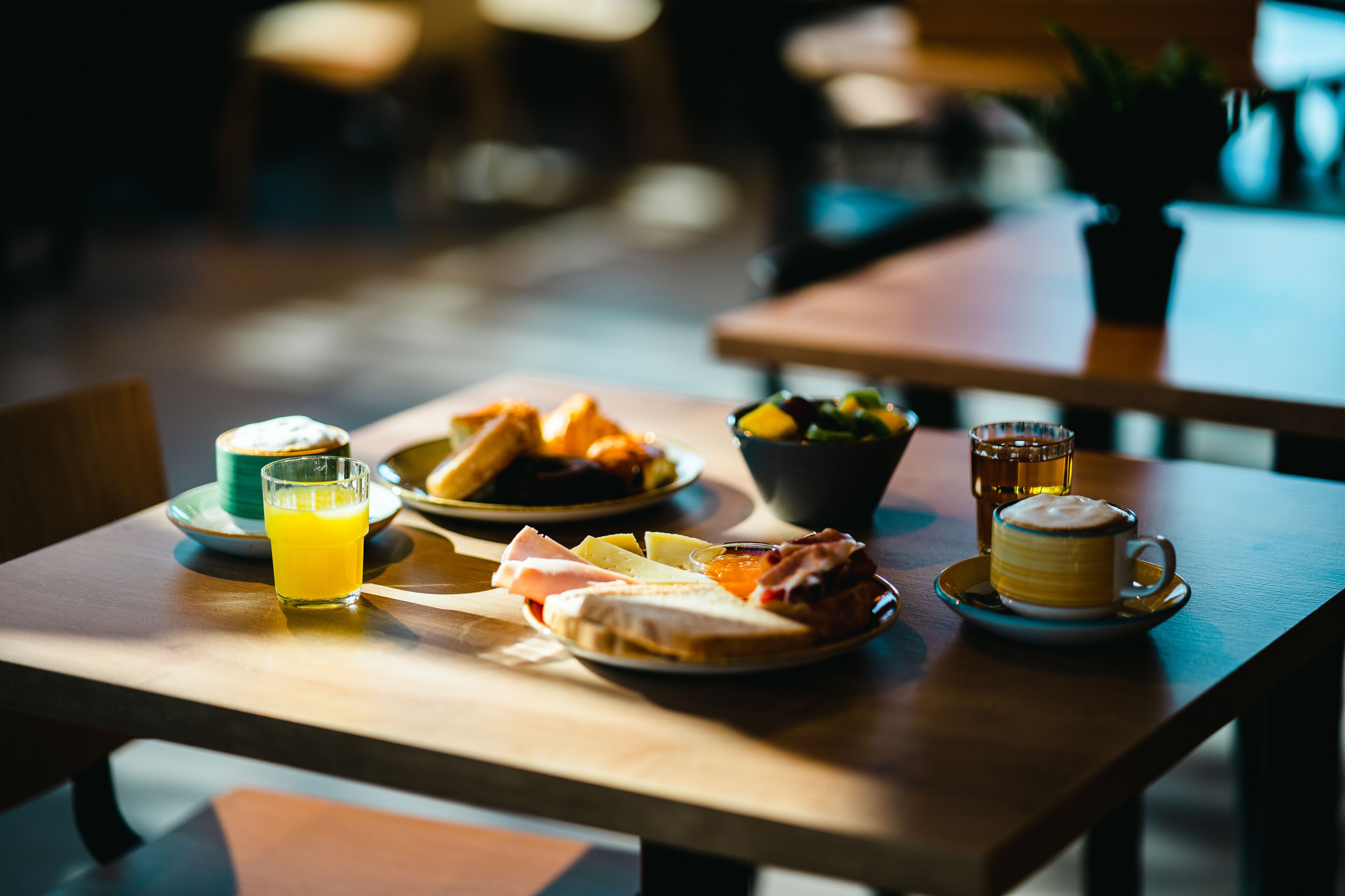 A breakfast setting with a wooden table, plates of food, a glass of orange juice, and a cup of coffee.